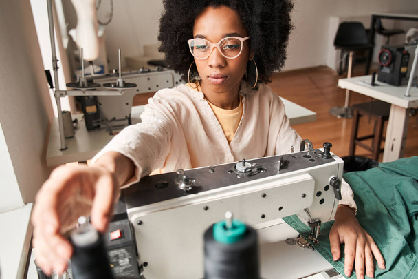 Multiracial woman sewing on an industrial re sewing clothes machine - Photo, Image
