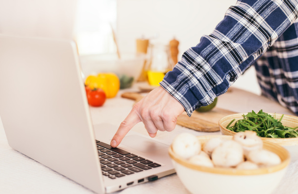 Sanal sanal sanatlar kursuna göre erkek pişirme ve dijital formüle bakarak evdeki mutfakta sağlıklı yemek pişirirken dizüstü bilgisayar kullanmak. Kapat.. - Fotoğraf, Görsel