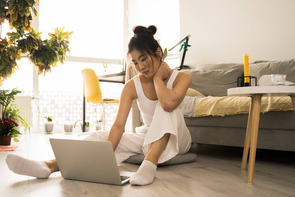 Asian woman sitting on the floor while writing email on laptop - Zdjęcie, obraz