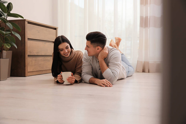 Happy couple lying on warm floor at home. Heating system - Photo, image