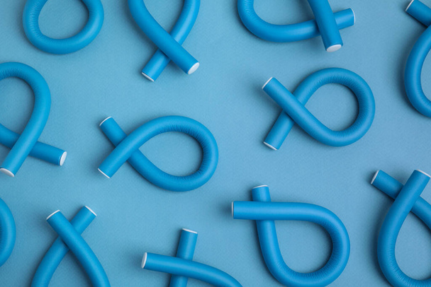 Curling rods on light blue background, flat lay. Hair styling tool - Фото, зображення