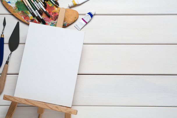 Blank canvas, tools and paints on white wooden table, flat lay. Space for text - Photo, image