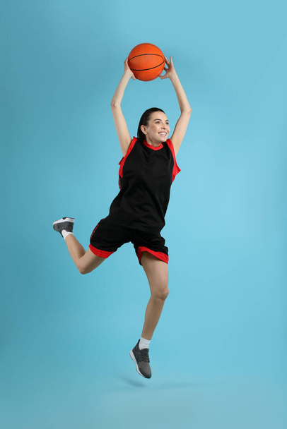 Professional sportswoman playing basketball on light blue background - Foto, afbeelding