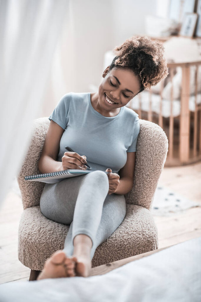 Joyful woman writing in notebook at home - Foto, Imagem