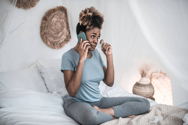 African American woman with smartphone and napkin near eyes - Valokuva, kuva