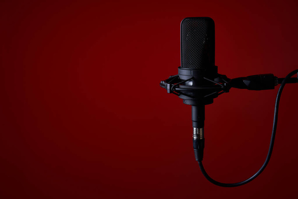Black studio condenser microphone on red background, with copy space on left - Zdjęcie, obraz