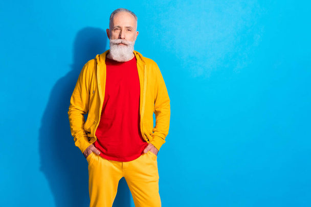 Photo portrait of old man wearing yellow tracksuit isolated on vibrant blue color background with copyspace - Photo, Image