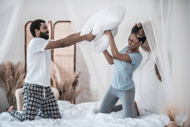 Husband and wife fighting pillows on bed - Foto, afbeelding