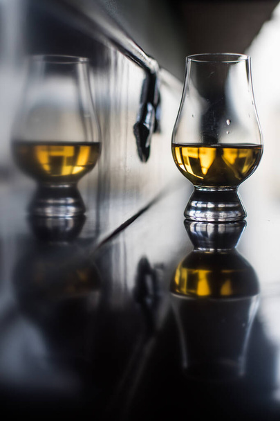 Kolorowe zbliżenie kieliszka Glencairn whisky na drewnianym stole, z płytką głębią ostrości. - Zdjęcie, obraz