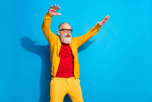 Photo of funky funny crazy excited mature man grandfather raise hands dancing isolated on blue color background - Fotoğraf, Görsel