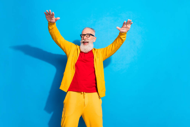 Photo of handsome smiling cheerful funky mature man in glasses dancing look copyspace isolated on blue color background - Fotoğraf, Görsel