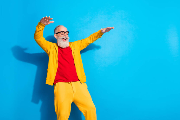 Photo of happy excited cheerful handsome funky grandfather in glasses dancing having fun isolated on blue color background - Foto, immagini
