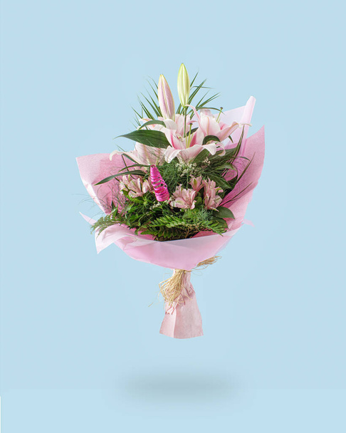 Un ramo de flores frescas de color rosa y blanco. Concepto creativo de color pastel de lirios. Fondo azul suave. - Foto, imagen