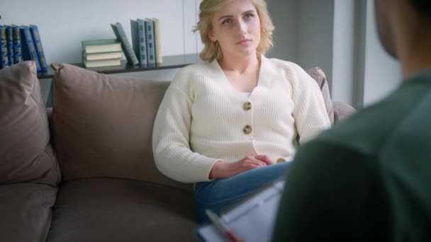 Überraschte junge Frau auf der Couch, die Probleme im Büro hört. Psychologische Therapie im Büro - Filmmaterial, Video