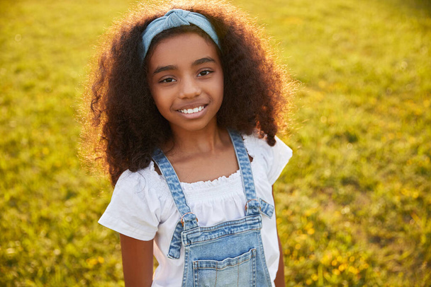 Delighted black girl looking at camera in summer park - Photo, Image