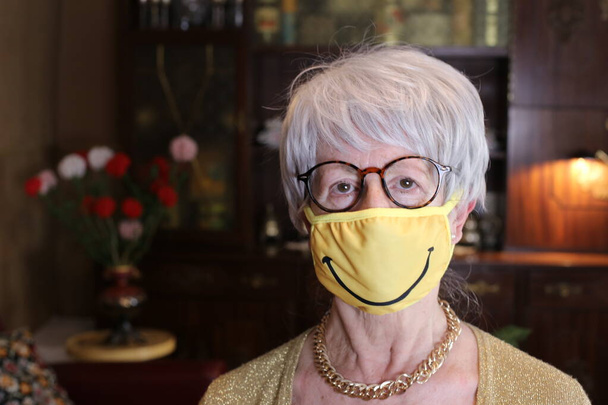 close-up retrato de mulher madura com máscara respiratória com sinal de sorriso em casa - Foto, Imagem