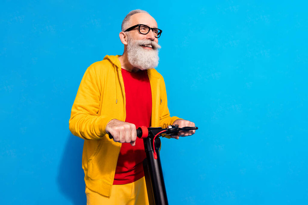 Profile portrait of cheerful aged man driving moped look empty space isolated on blue color background - Fotografie, Obrázek