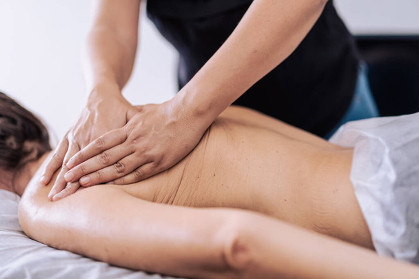 Femme recevant un massage du dos dans un centre de spa. La patiente reçoit un traitement par un thérapeute professionnel. - Photo, image