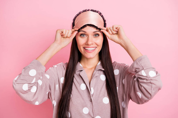 Photo of cute sweet young lady dotted nightwear arms mask smiling isolated pastel pink color background - Foto, afbeelding