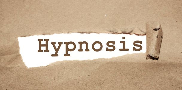 Hypnose-Wort, das hinter zerrissenem braunem Papier erscheint. Psychologisches Gesundheitskonzept zur Stressreduzierung. - Foto, Bild