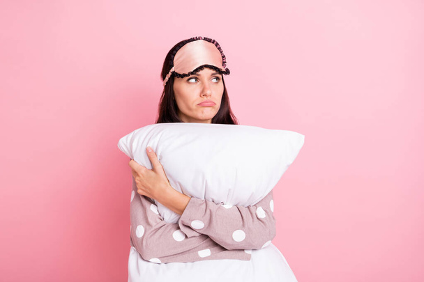 Photo of upset tired young lady nightwear mask hugging white pillow looking empty space isolated pink color background - Foto, Bild