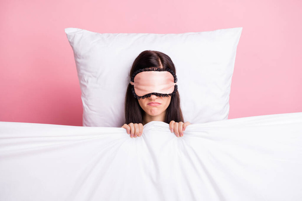 Photo of cute tired young lady dotted nightwear mask cover face lying pillow under blanket isolated pink color background - Fotó, kép