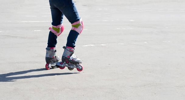 Primer plano perfil recortado, vista lateral de los pies de los niños en vaqueros azules, patinaje sobre hielo divertirse sobre fondo gris - Foto, Imagen