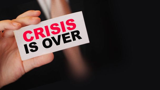 La crisis ha terminado con las palabras en la tarjeta que el Empresario está sosteniendo. Word Crisis, gestión de riesgos en el concepto empresarial. - Foto, Imagen