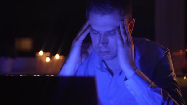 Väsynyt ylityöllistetty mies työskentelee kannettavan tietokoneen tietokoneen myöhään illalla. - Materiaali, video