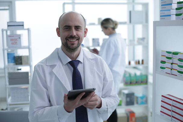 Pharmacists is Working. Man and Woman. People Wearing Special Medical Uniform. Man holding tablet in hands. People Located in Pharmacy. - Foto, immagini