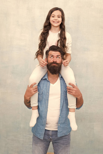 Growing mustache is fun. Little daughter twist fathers moustache. Happy family grey background. Bearded man ride child on shoulders. Family values. Trust relationship. Love and care - Foto, Imagem
