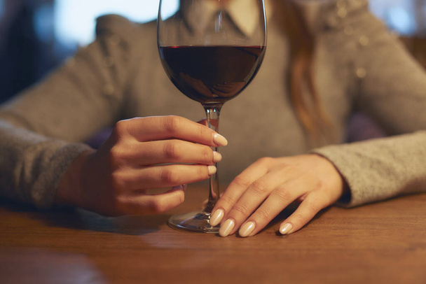 Hand of a young beautiful girl holding a glass of wine indoors of a stylish wine restaurant - Fotoğraf, Görsel