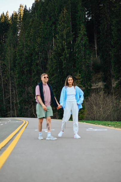 Rozmazané abstraktní fotografie, zaměření na les, pár muž a žena kráčející po silnici v horském lese držící se za ruce. - Fotografie, Obrázek