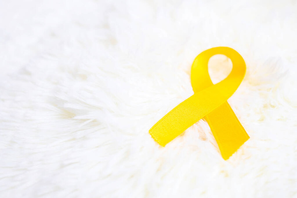 Beyaz arka planda sarı kurdele yaşayan ve hastalıklı insanları desteklemek için. Eylül İntihar Önleme Günü, Sarkoma Kanseri ve Çocukluk Kanseri Farkındalığı Ayı konsepti - Fotoğraf, Görsel