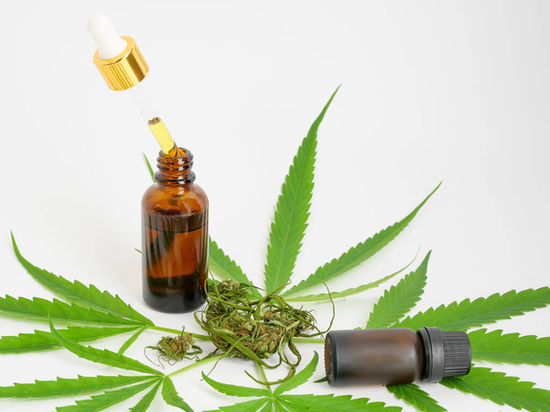 Μπουκαλάκι γυάλινο CBD λάδι κάνναβης εκχύλισμα φύλλα μαριχουάνας και οφθαλμός σε λευκό φόντο, Ιατρική έννοια βότανο. - Φωτογραφία, εικόνα