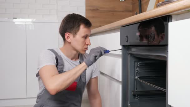 τεχνίτης ανατροπές βίδες στο φούρνο για να βρείτε ελάττωμα στην κουζίνα - Πλάνα, βίντεο