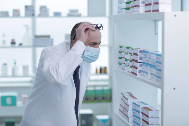 Man pharmacist in protective face mask working in drugstore - Φωτογραφία, εικόνα