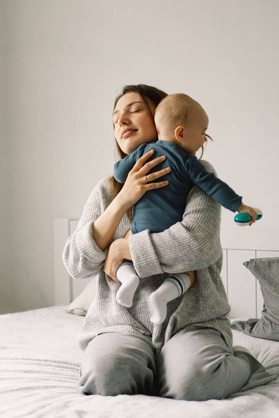 Egy fiatal anya játszik a kisfiúval. Egy szoptató csecsemő anyja. Boldog anyaságot! A család otthon van. Egy boldog anya és gyermek portréja. - Fotó, kép