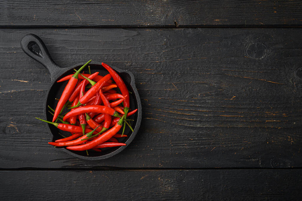 Ripe Cayenne pepper set, on black wooden table, top view flat lay, with copy space for text - 写真・画像