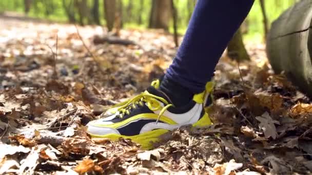 Una chica en zapatillas amarillas mueve sus pies sobre hojas secas en el bosque. Togliatti, Rusia - 13 de mayo de 2021 - Metraje, vídeo