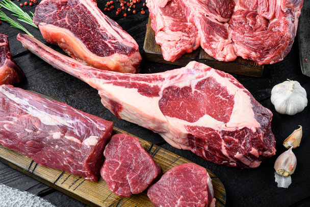 トマホーク生の新鮮な牛肉ステーキスパイスセット,調味料やハーブと,黒の木製のテーブルの背景に,トップビューのフラットレイアウト - 写真・画像
