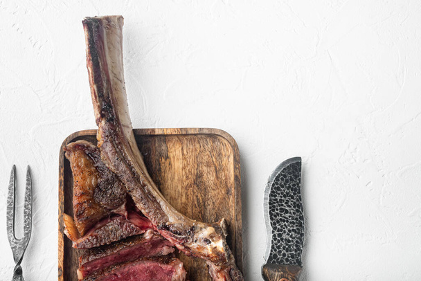 Medium rare Tomahawk meat marbled dry aged beef grilled set, on wooden serving board, on white stone  background, top view flat lay, with copy space for text - Photo, Image
