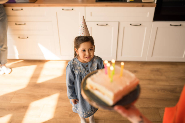 Chica mirando su pastel de cumpleaños mientras se prepara para soplar las velas - Foto, imagen