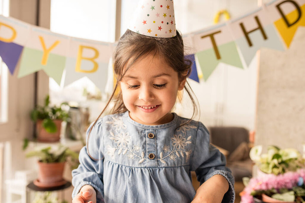 Girl looking down with smile while preparing to the celebration of her birthday - Photo, image