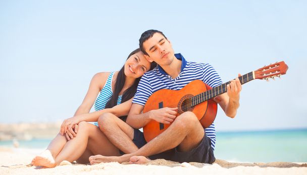 Молода пара з гітарою на пляжі в літній день
. - Фото, зображення