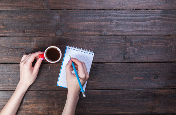 Hands holding notebook and coffee cup. - Photo, Image