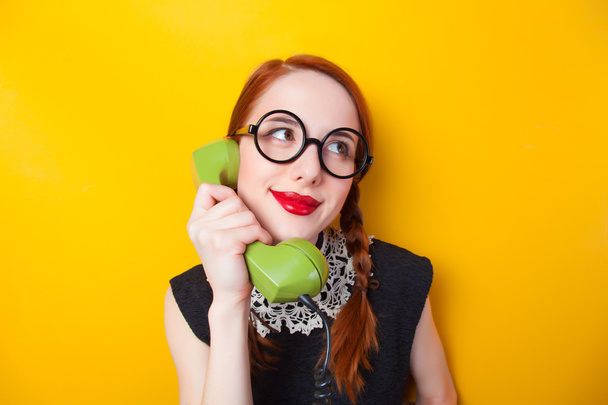 rothaarige Mädchen mit grünem Telefon auf gelbem Hintergrund. - Foto, Bild