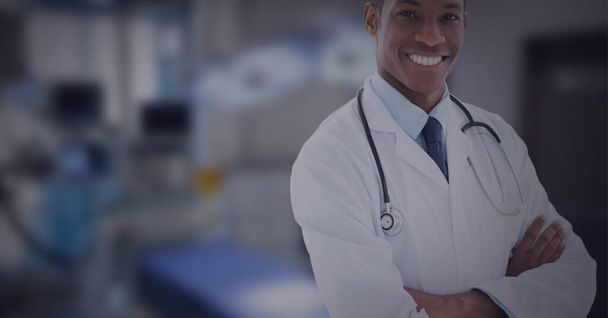 Portrait of african american male doctor smiling against operation theatre in background. healthcare and medical professionalism concept - Foto, Imagem