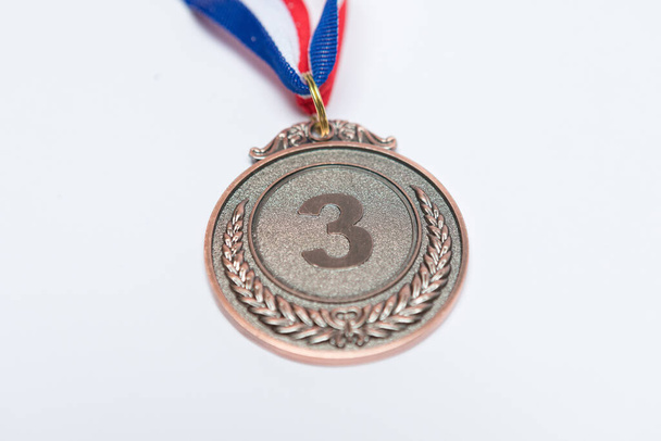 Bronzen medaille van sportieve prestatie voor de derde geclassificeerd, op een witte achtergrond. Olympische Spelen en sportconcept - Foto, afbeelding