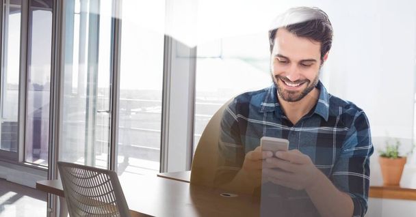 Composition of smiling man using smartphone in office with white overlay. global networking, business and technology concept digitally generated image. - Photo, image